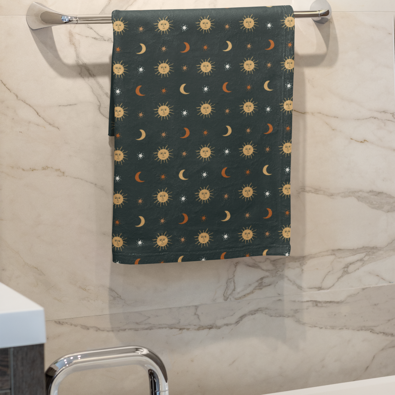 Towel with celestial pattern hanging on a towel rack in a bathroom.