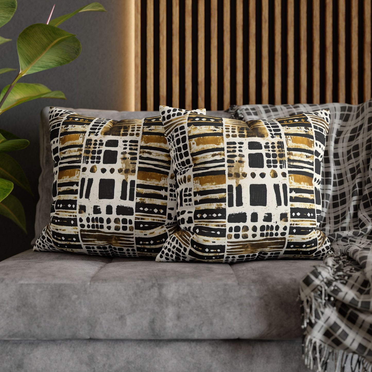 Patterned cushions on a gray sofa with a plant and wooden headboard in the background