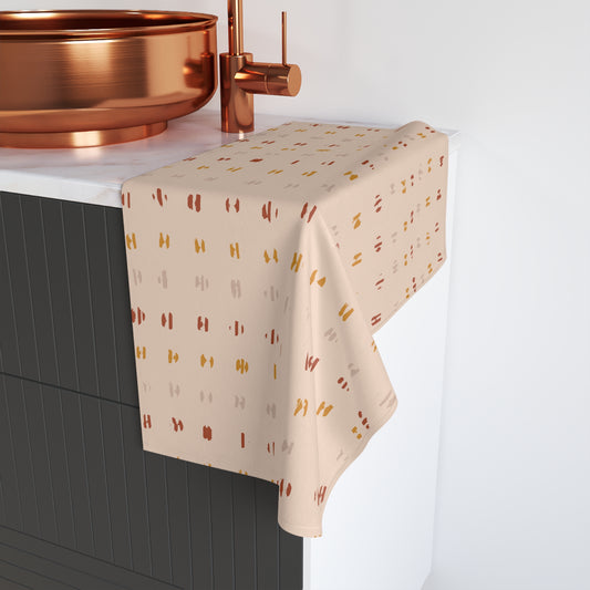 Abstract stripe hand towel with pattern draped over a black cabinet with copper fixtures.