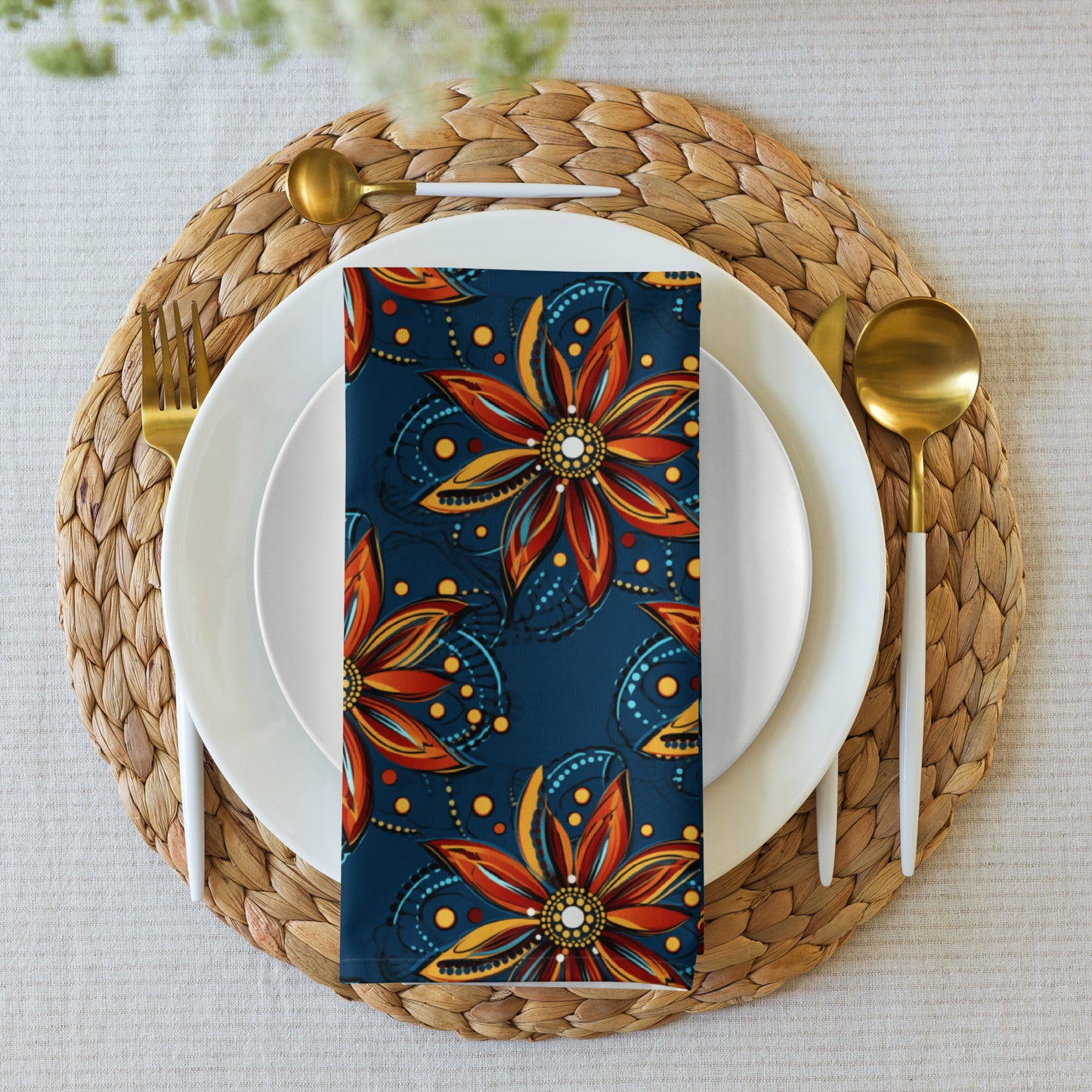 Decorative floral-patterned napkin on a place setting with gold cutlery and woven placemat.