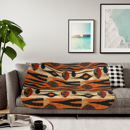 Colorful African art patterned blanket on a sofa with a plant and framed pictures in the background.