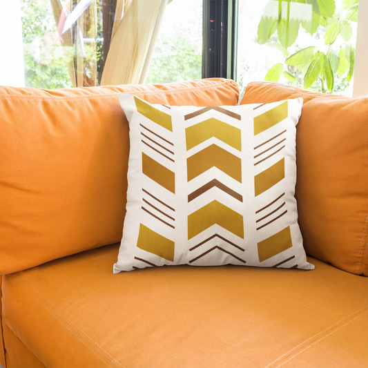 Orange sofa with a decorative pillow featuring a geometric pattern in a room with windows and greenery.