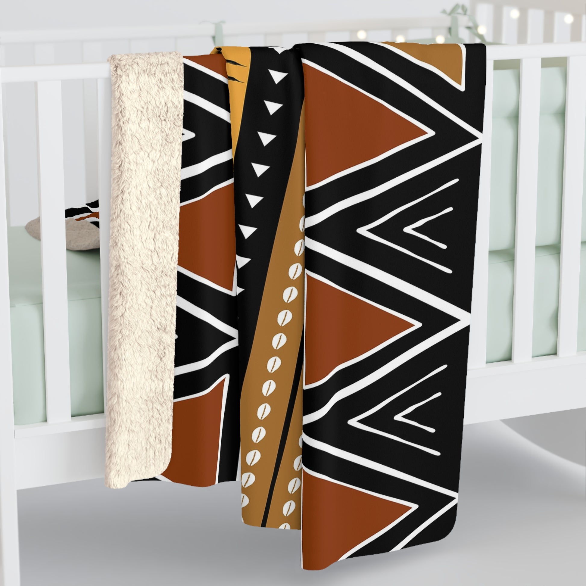 Decorative blanket with tribal pattern draped over a crib in a nursery.