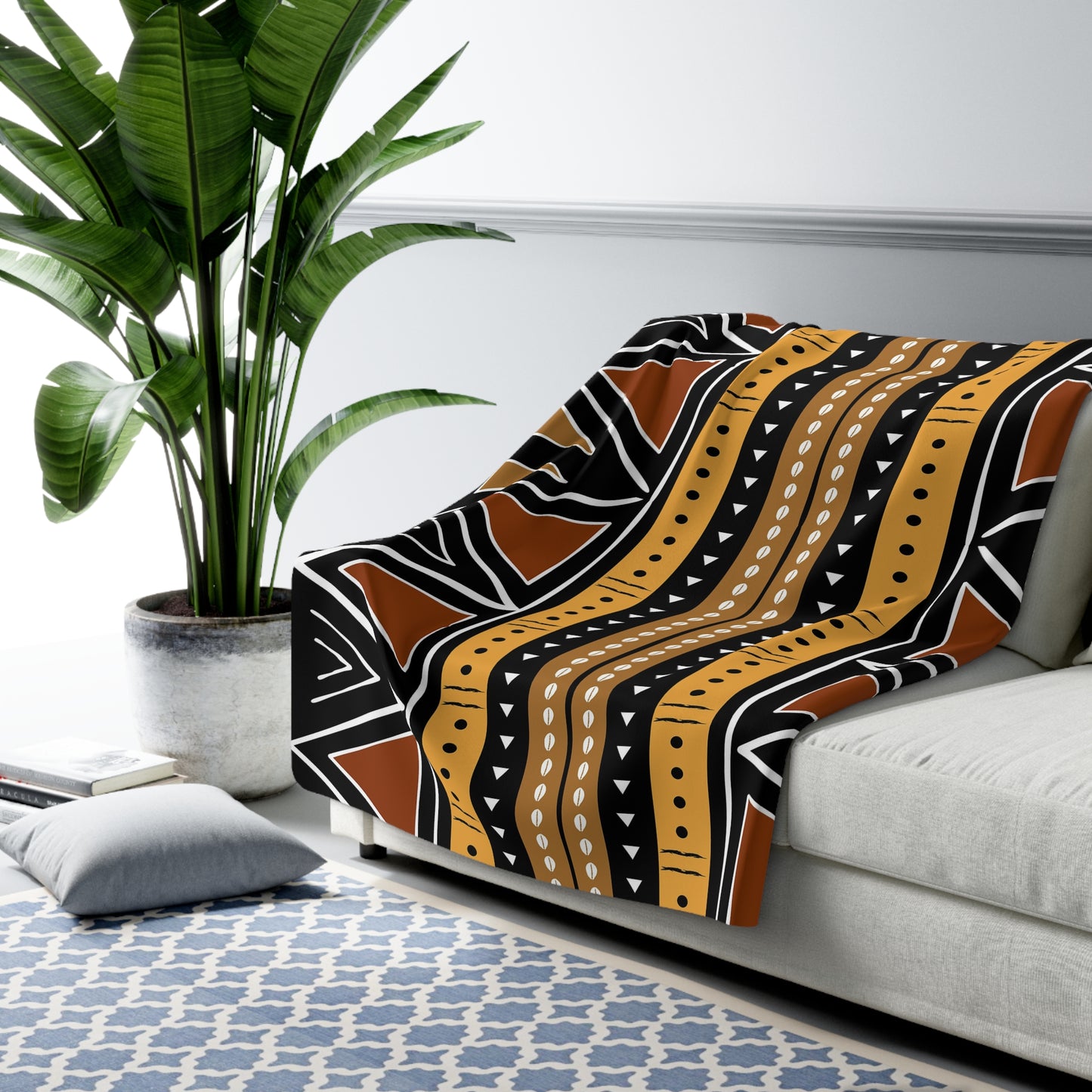 Mudcloth Patterned blanket draped over a sofa in a living room with a plant and rug.