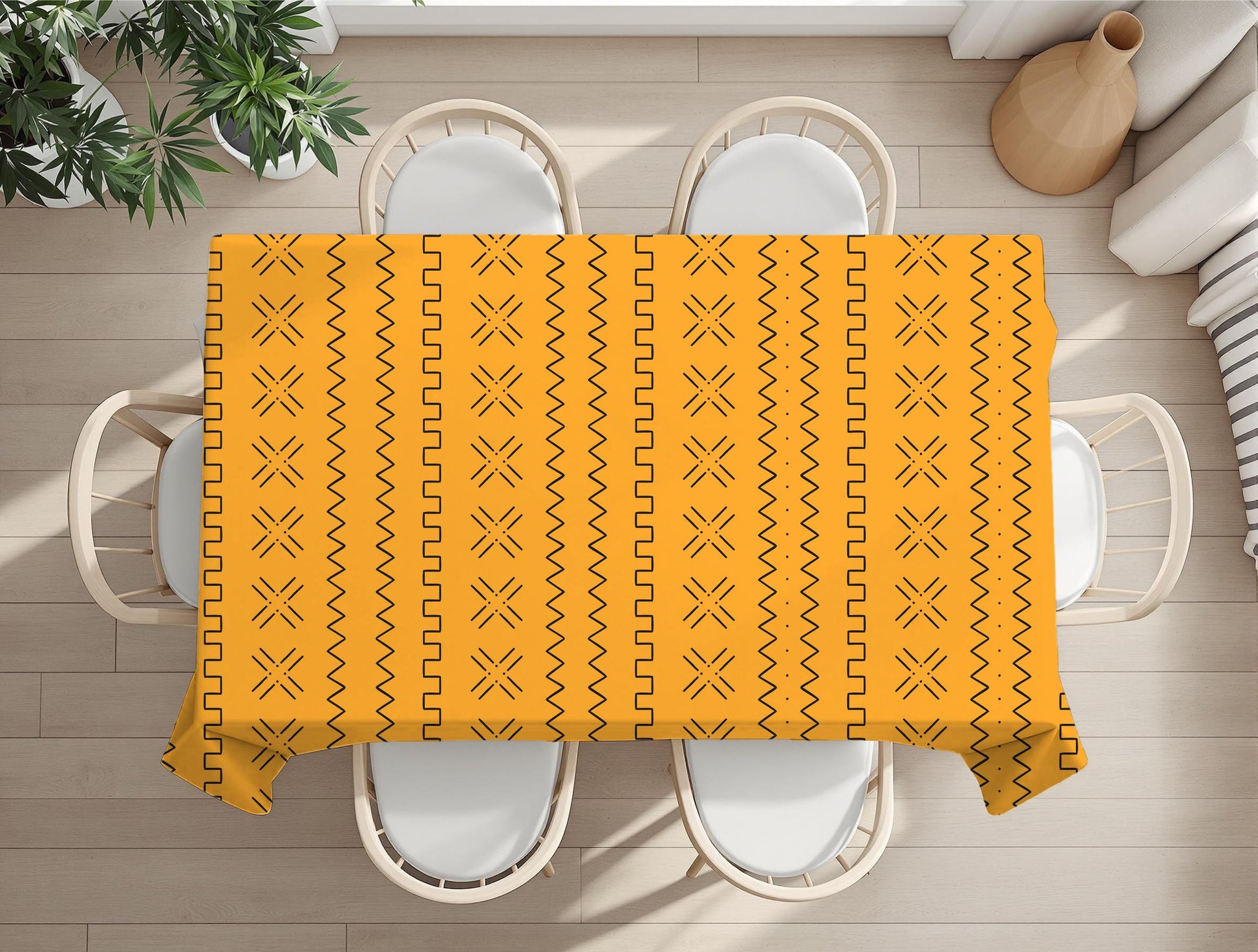 Yellow Geometric patterned tablecloth on a wooden table with white chairs and plants.