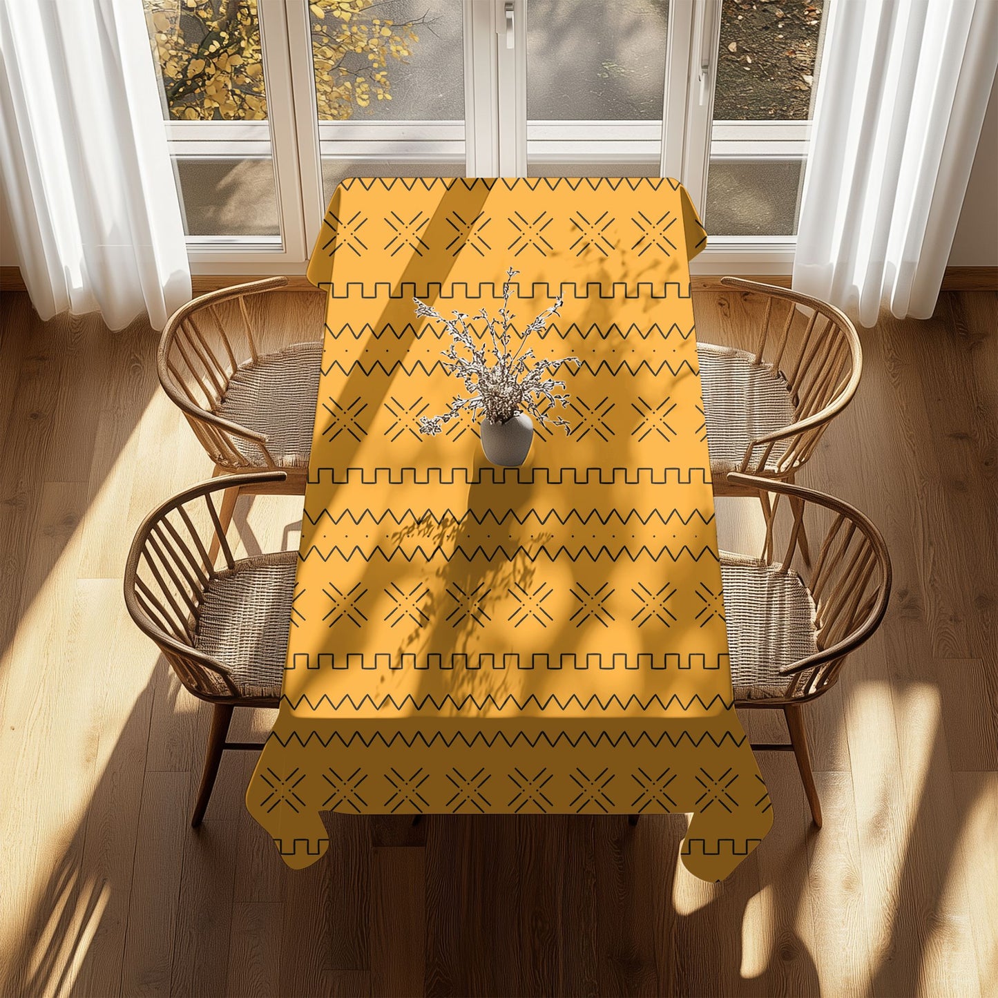 A mustard yellow tablecloth with African Mudcloth and Tribal Print patterns laid on a table with plates and chairs.