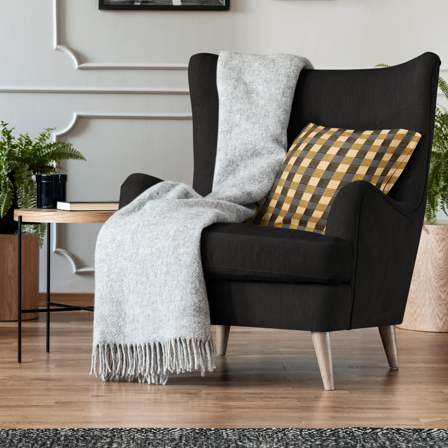 Black armchair with a gray throw and yellow checkered pillow in a living room setting.