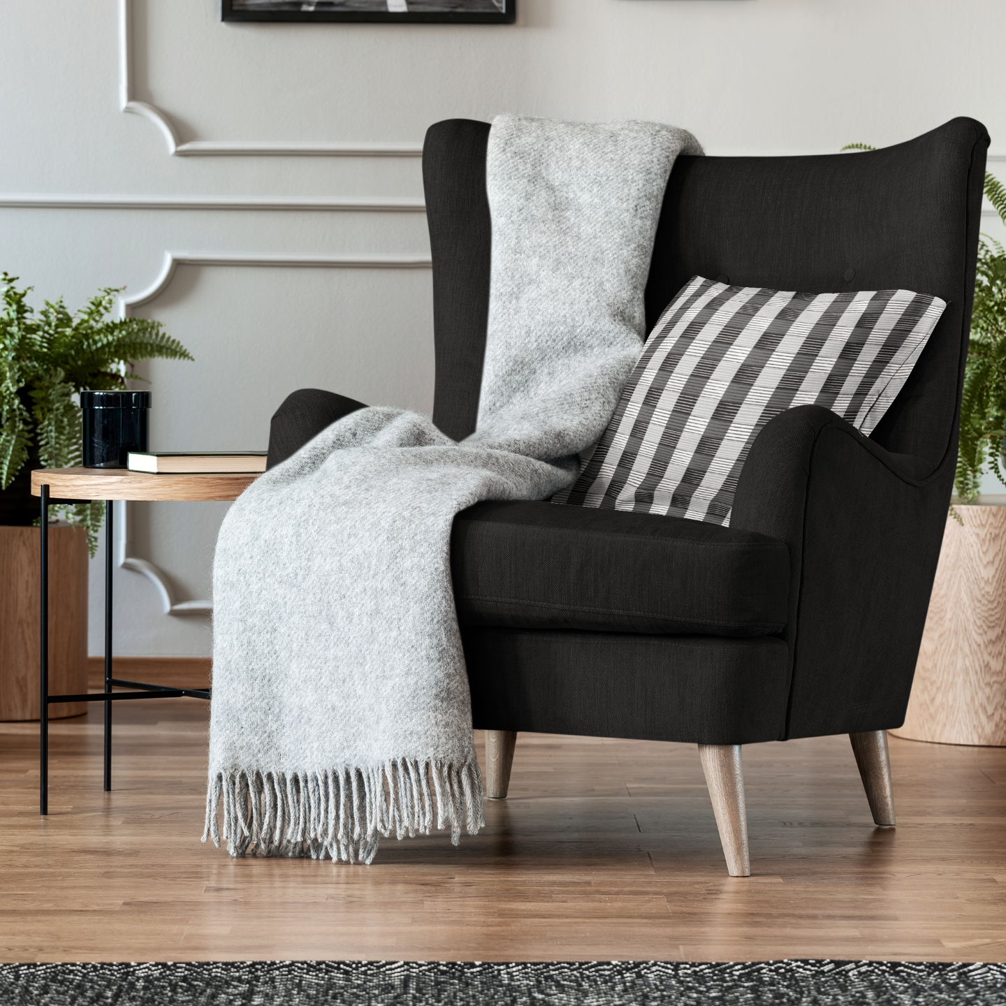 Black armchair with a gray blanket and striped pillow in a living room setting.