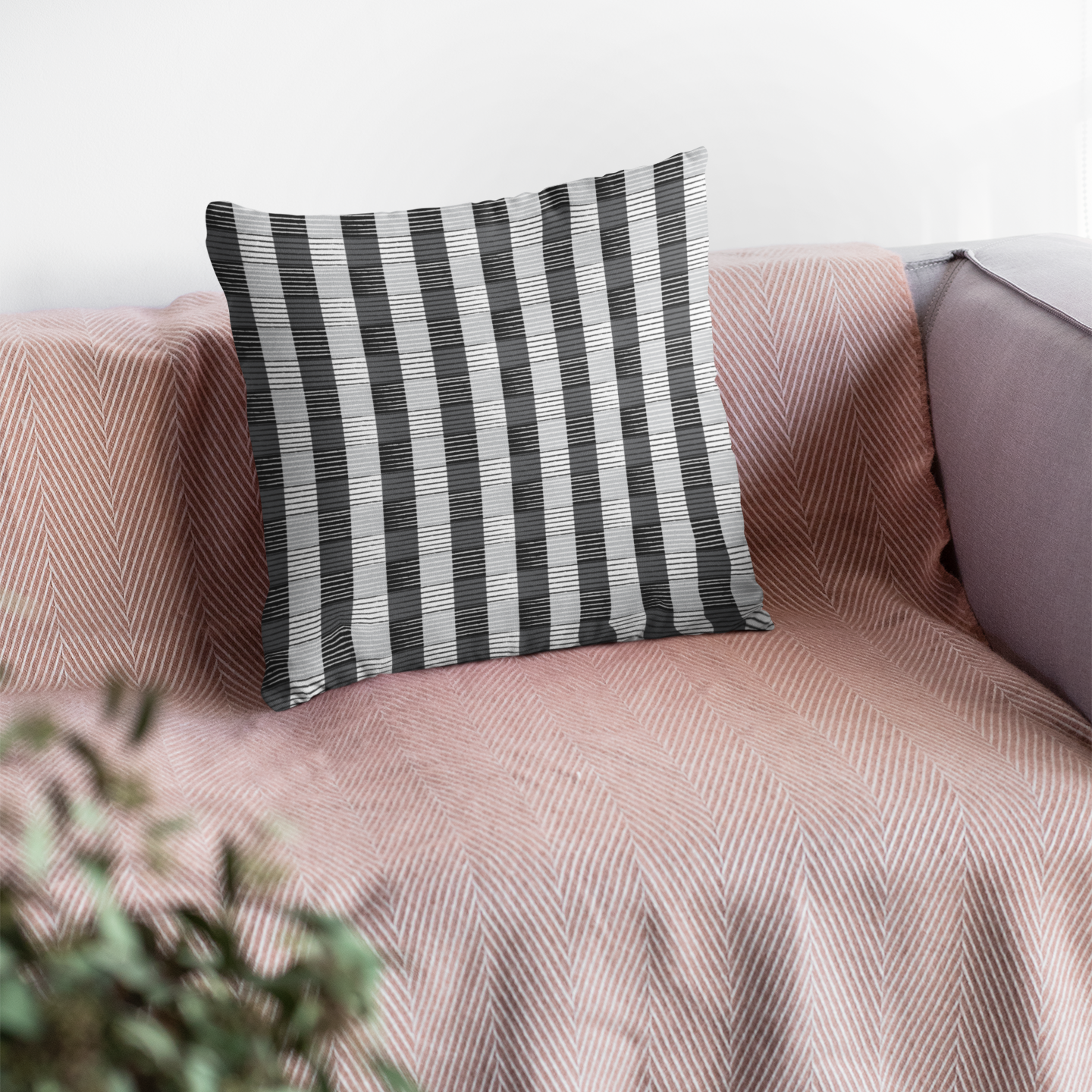 Striped pillow on a pink sofa with a blurred plant in the foreground