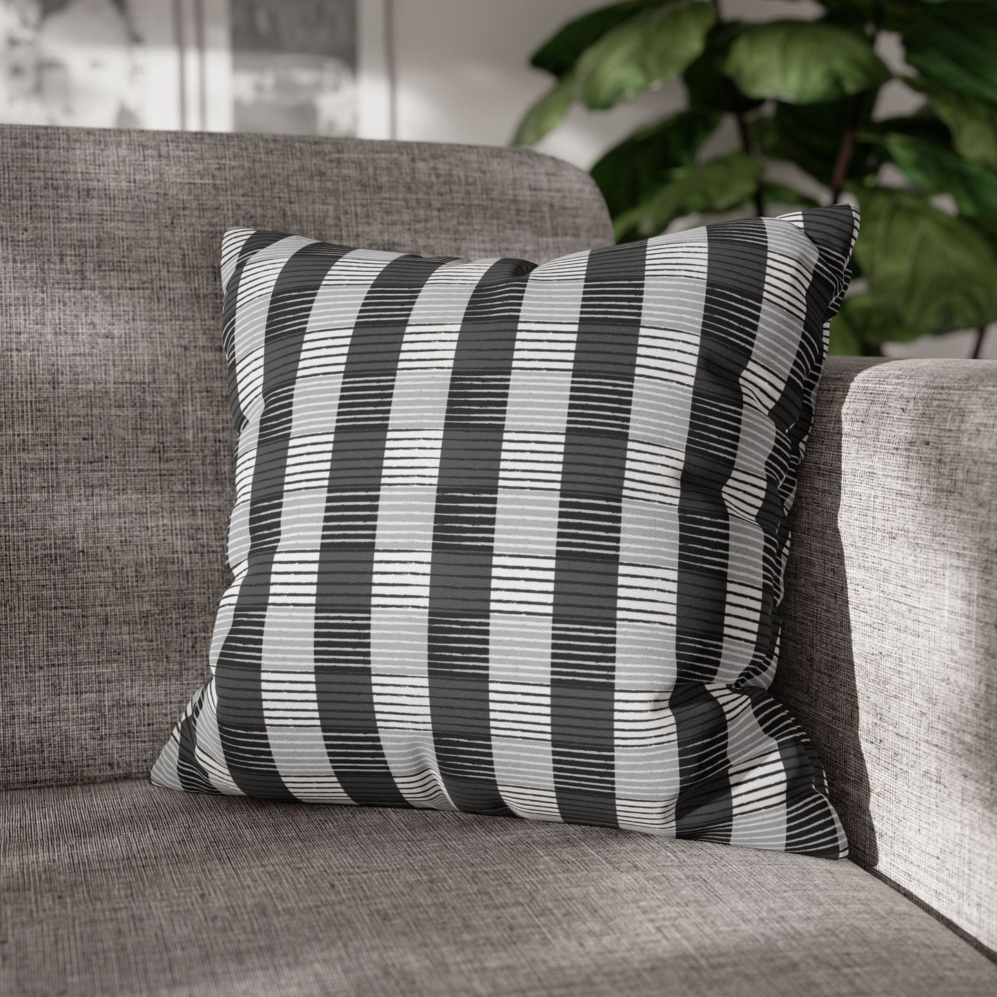 Two square throw pillows with a striped African Plaid pattern in beige and black colors, placed on a gray sofa.