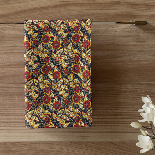 Patterned towel hanging on a wooden wall with a candle and plant in the foreground.