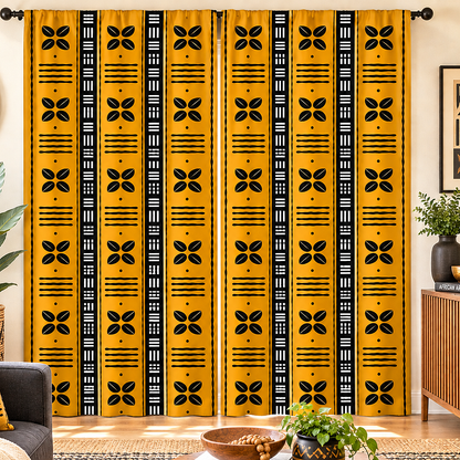 A pair of floor-length curtains hanging in a living room setting, featuring a bold yellow fabric with vertical black geometric and floral patterns.