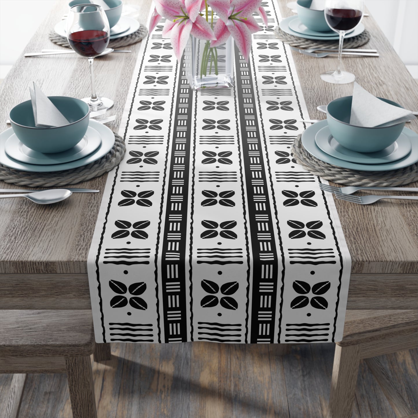 A black and white mudcloth style table runner with geometric patterns displayed on a dining table.