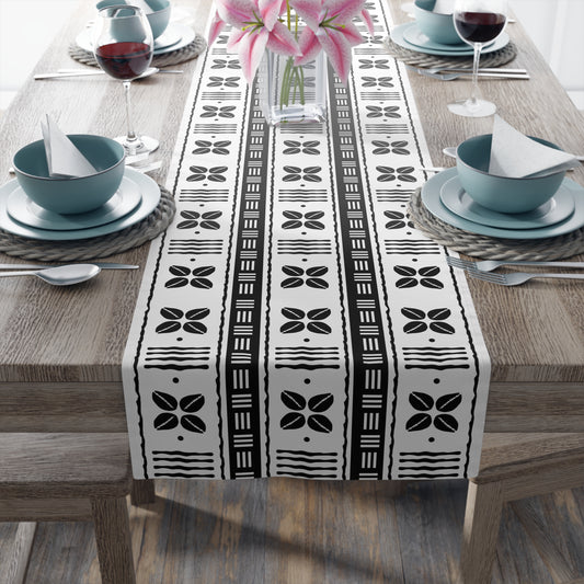 A black and white mudcloth style table runner with geometric patterns displayed on a dining table.