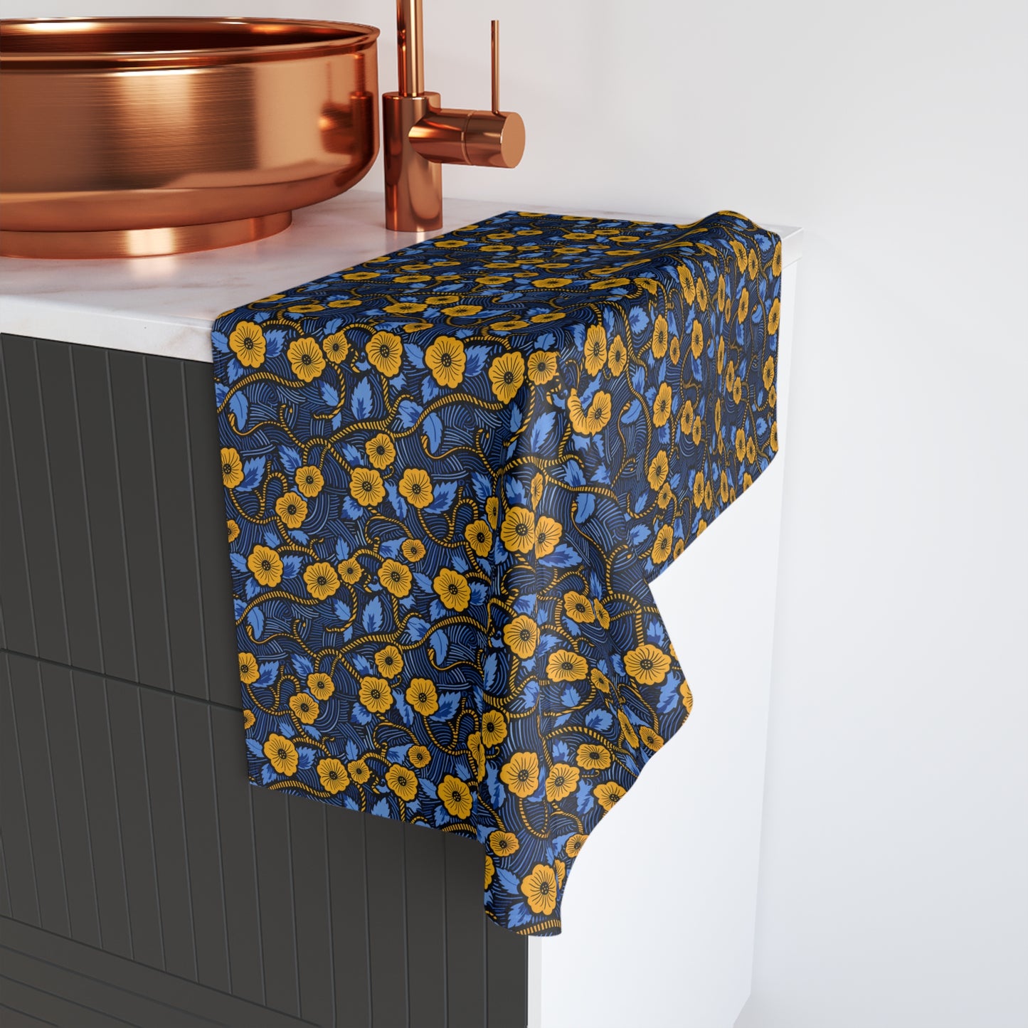 Floral patterned towel draped over a sink with copper fixtures.