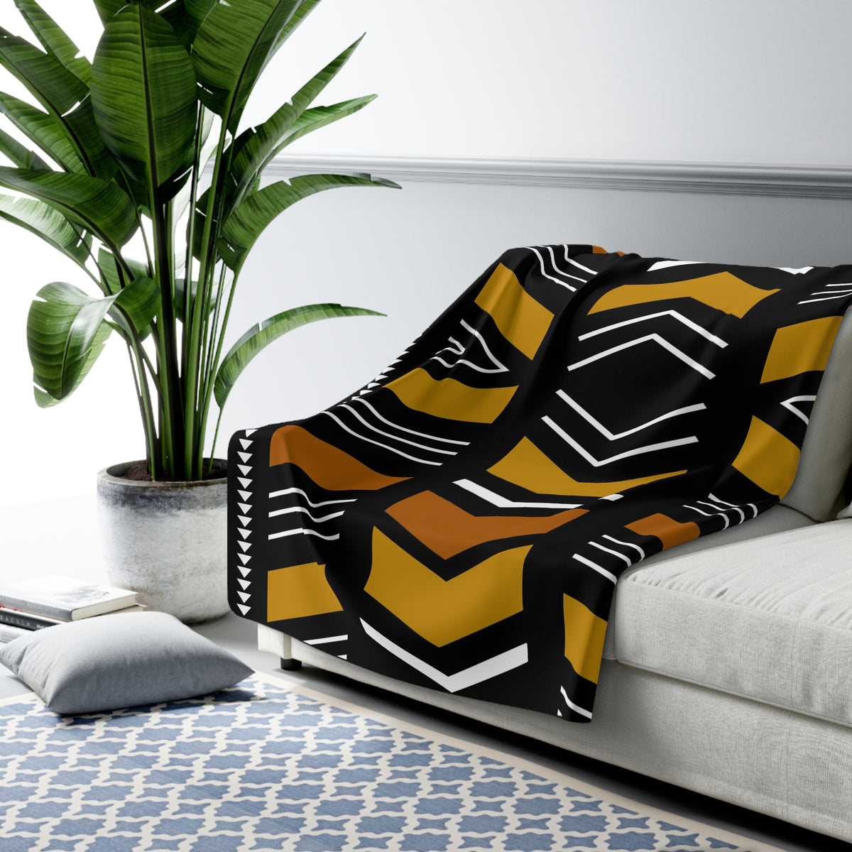 Black and yellow patterned blanket draped over a sofa in a living room setting with a plant and rug.