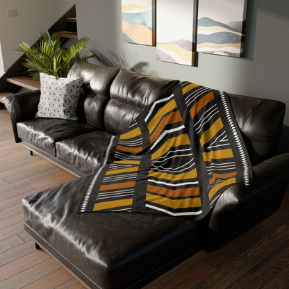 Striped blanket draped over a brown leather sofa in a living room setting.
