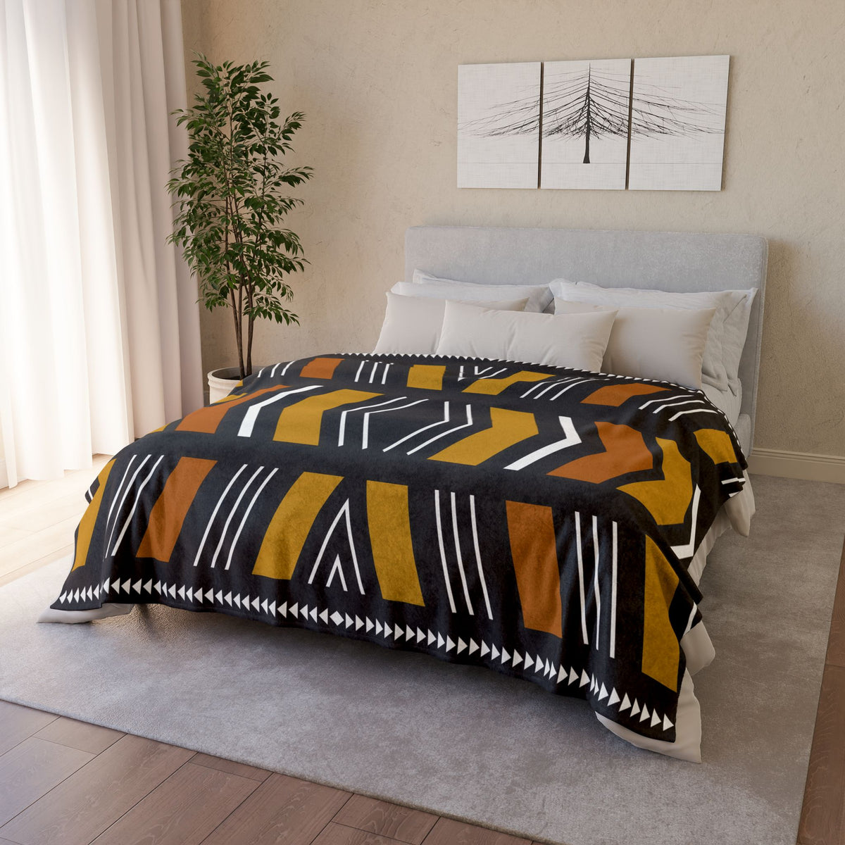 Bedroom with a bed covered by a patterned comforter, plant, and wall art.