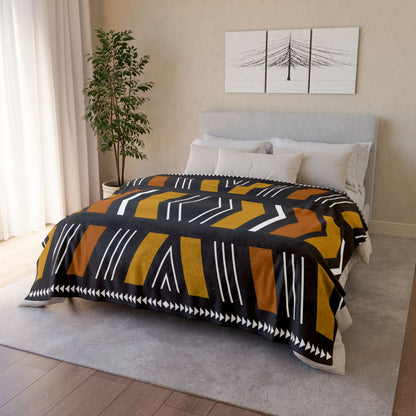 Bedroom with a bed covered by a patterned comforter, plant, and wall art.