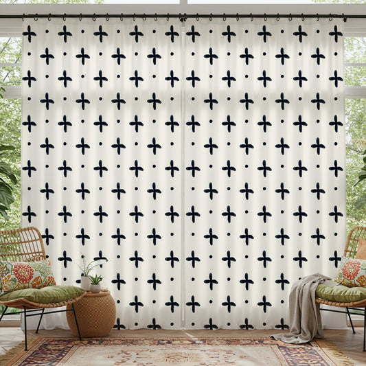 Window Curtains with black cross pattern in a bright room with plants and furniture.