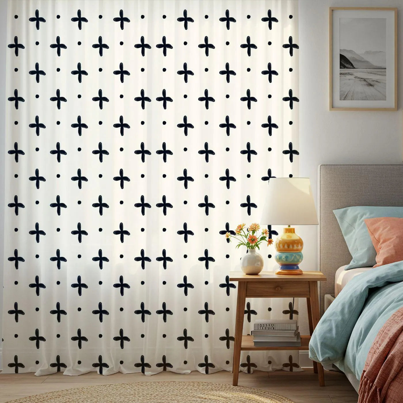 Room with a curtain featuring black cross patterns, a side table with decor items, and a bed.