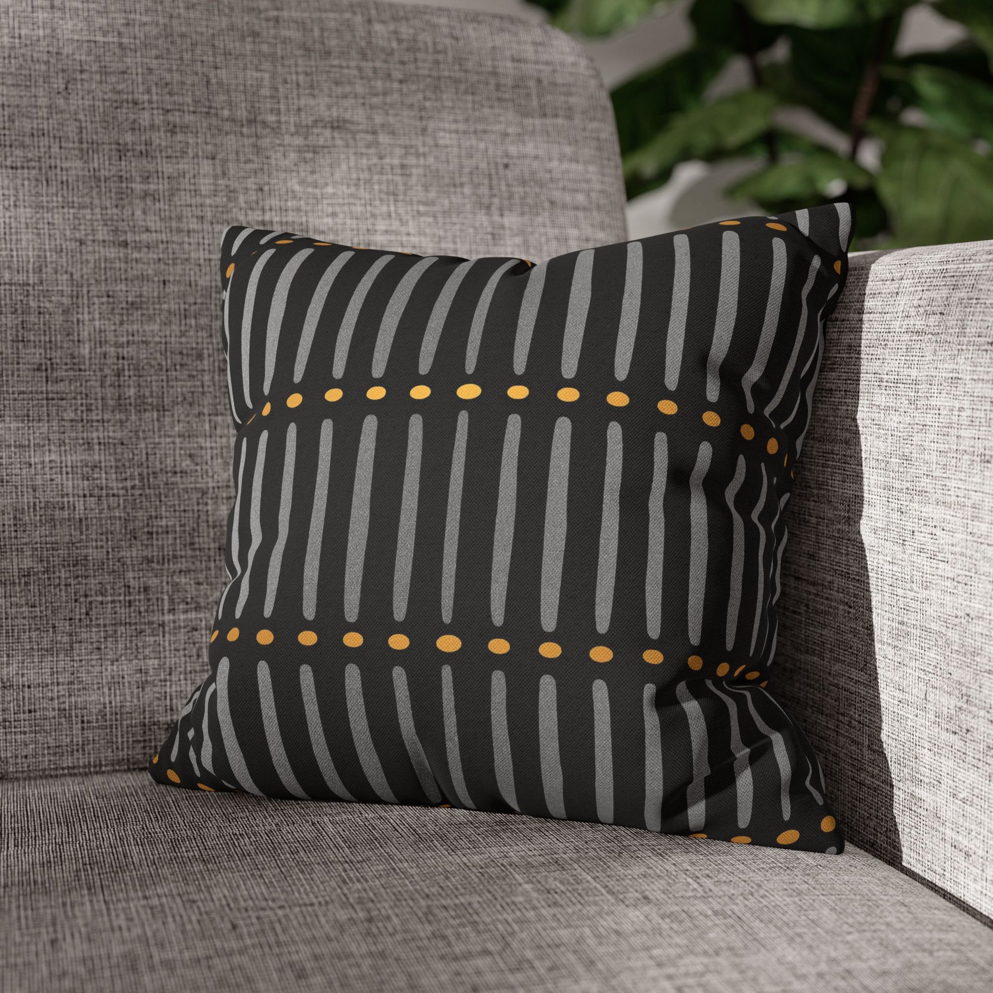 Mudcloth pillow with black and gray striped pattern on a gray sofa.
