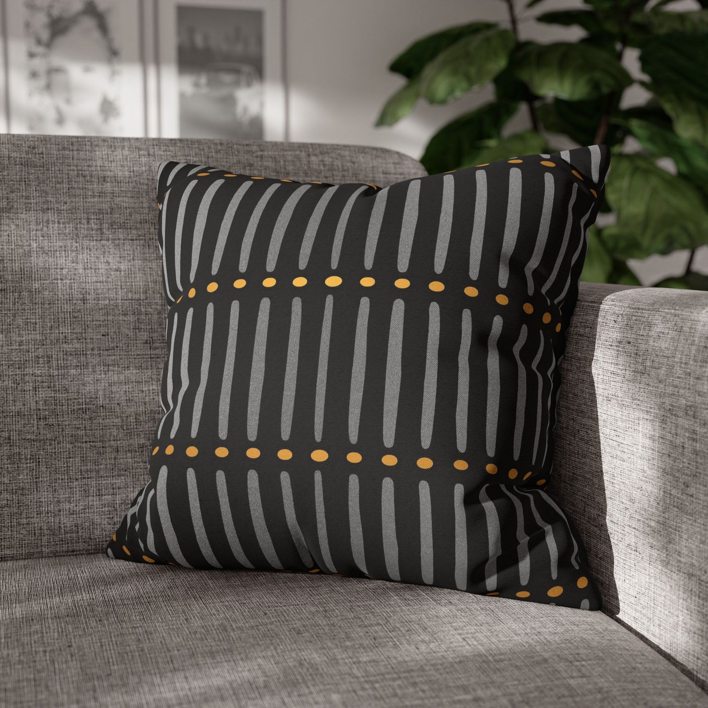 Mudcloth pillow with black and gray striped pattern on a gray sofa