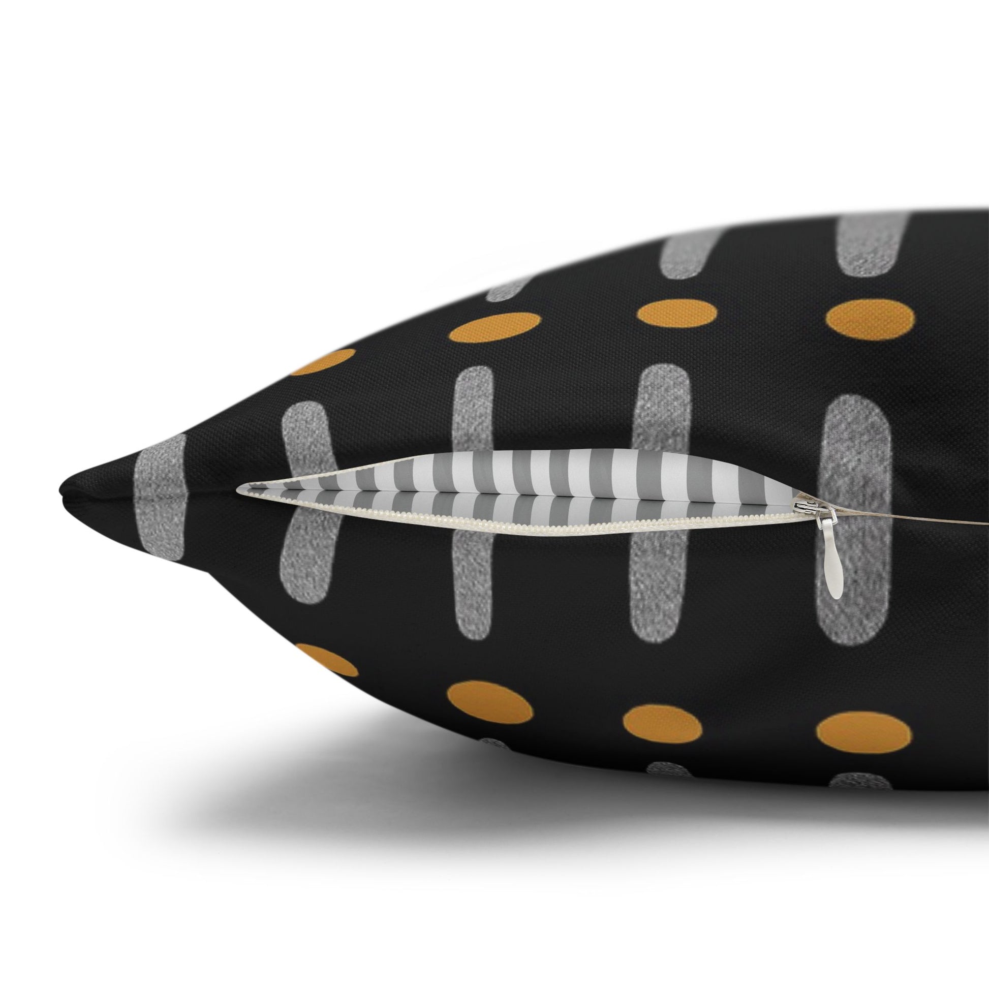 Tribal pillow with black background, gold polka dots, gray stripes, and a white feather.