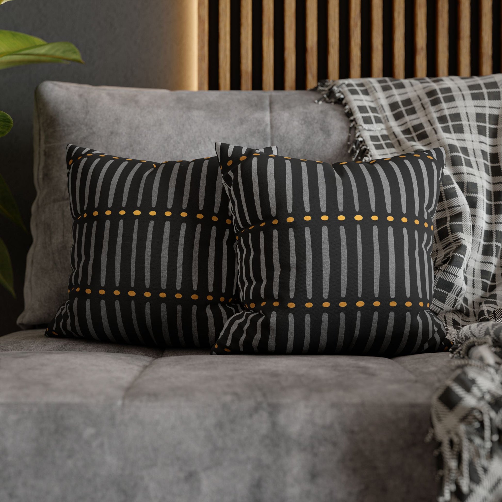 Black and white striped pillows with gold accents on a gray sofa.