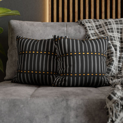 Black and white striped pillows with gold accents on a gray sofa.