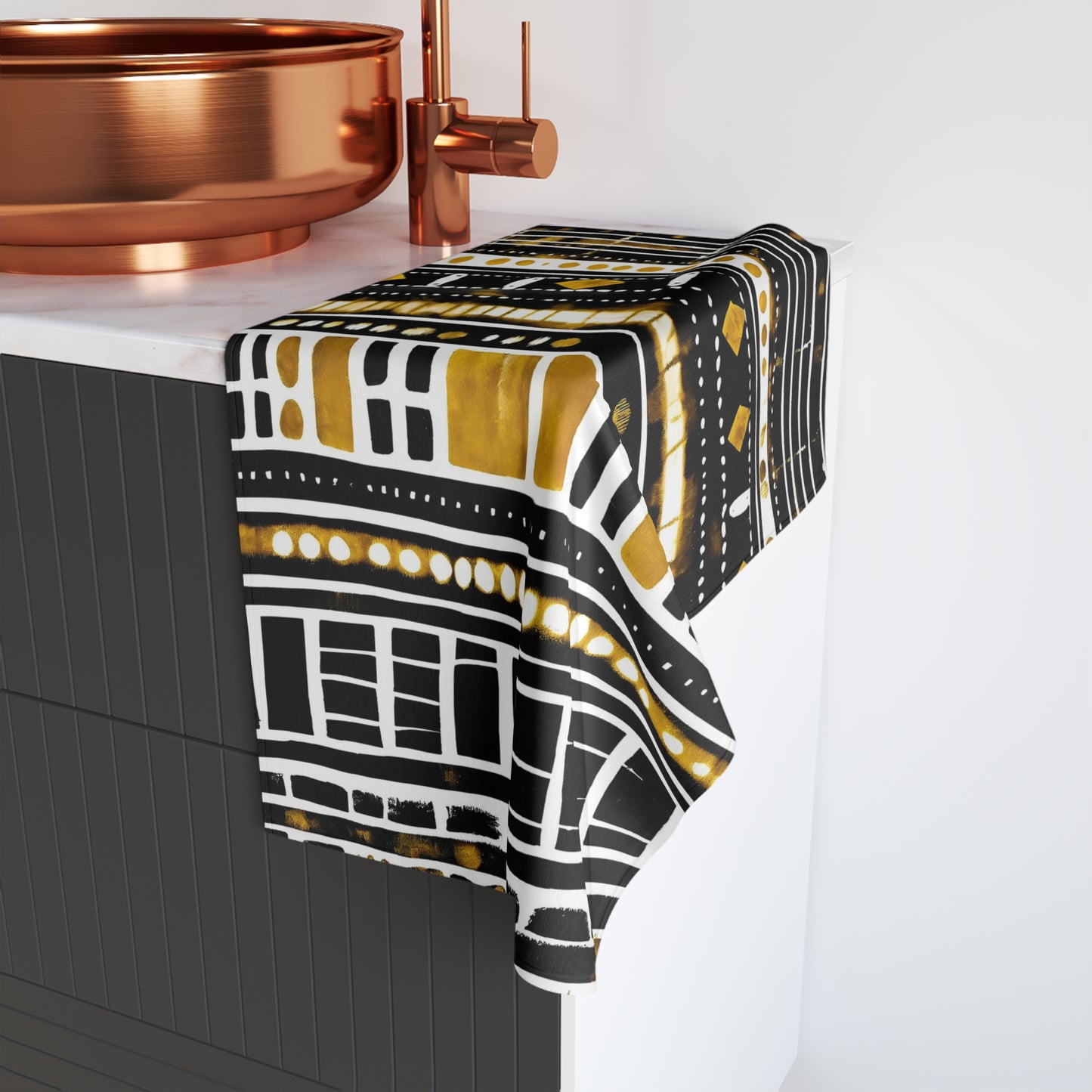 Patterned towel draped over a kitchen counter with copper fixtures.