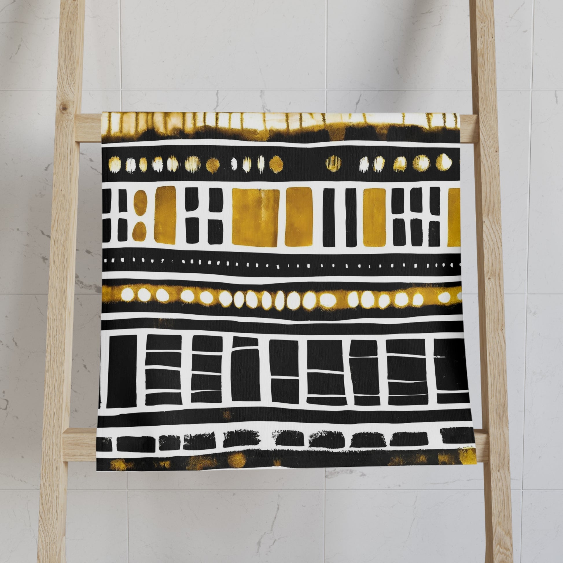 Decorative towel with black, white, and gold pattern on a wooden ladder against a white wall.