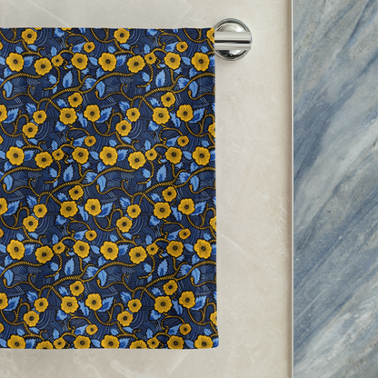 African print towel with yellow floral pattern hanging on a rack against a marble wall.