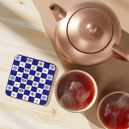 Teapot and cups of tea on a wooden surface with a decorative coaster.