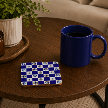 Blue mug on a wooden table with a checkered coaster, candle, and plant.