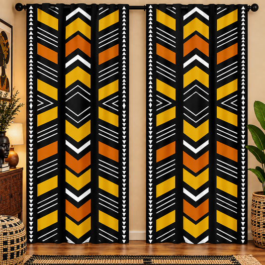 A pair of floor-length curtains hanging on a rod in a room. The curtains feature a bold African-inspired geometric pattern with vertical stripes of yellow, orange, black, and white chevrons and triangles.