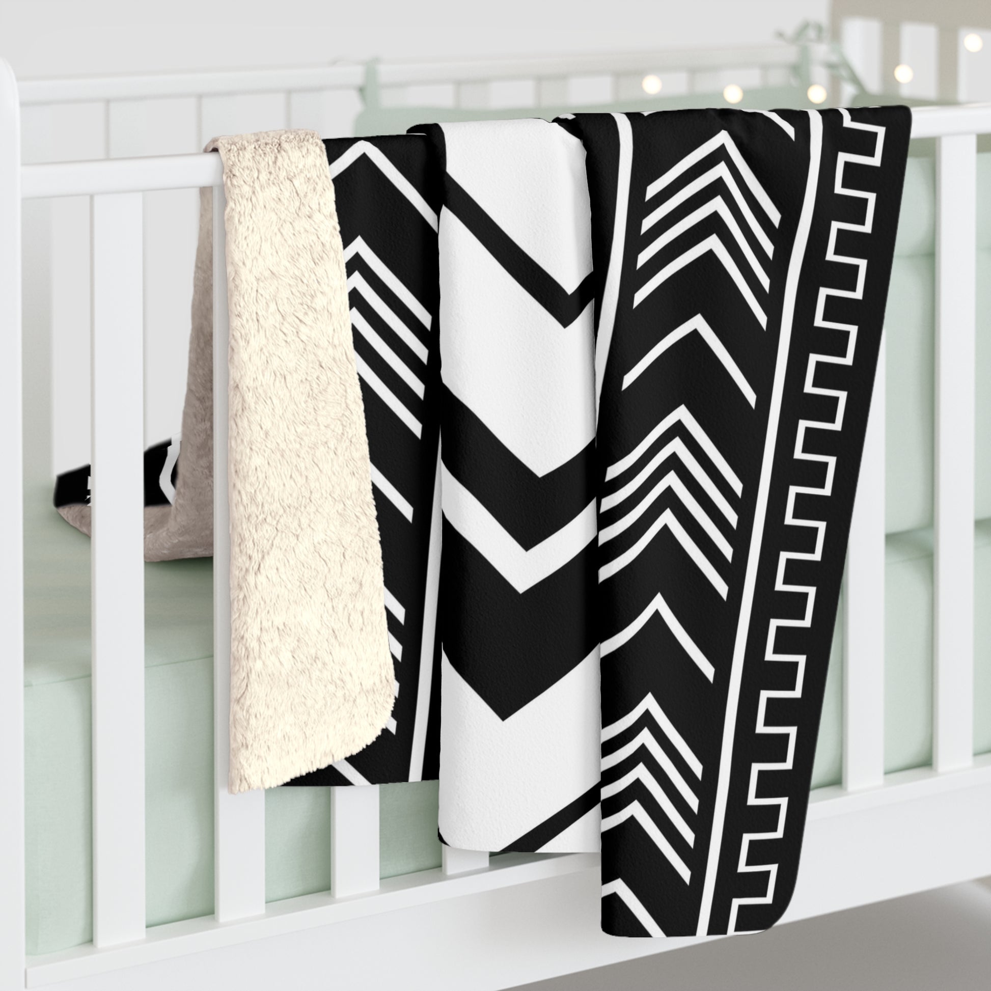 Black and white patterned blanket draped over a white crib