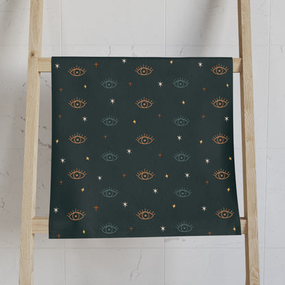 Teal Green towel with eye pattern on a wooden ladder against a white wall
