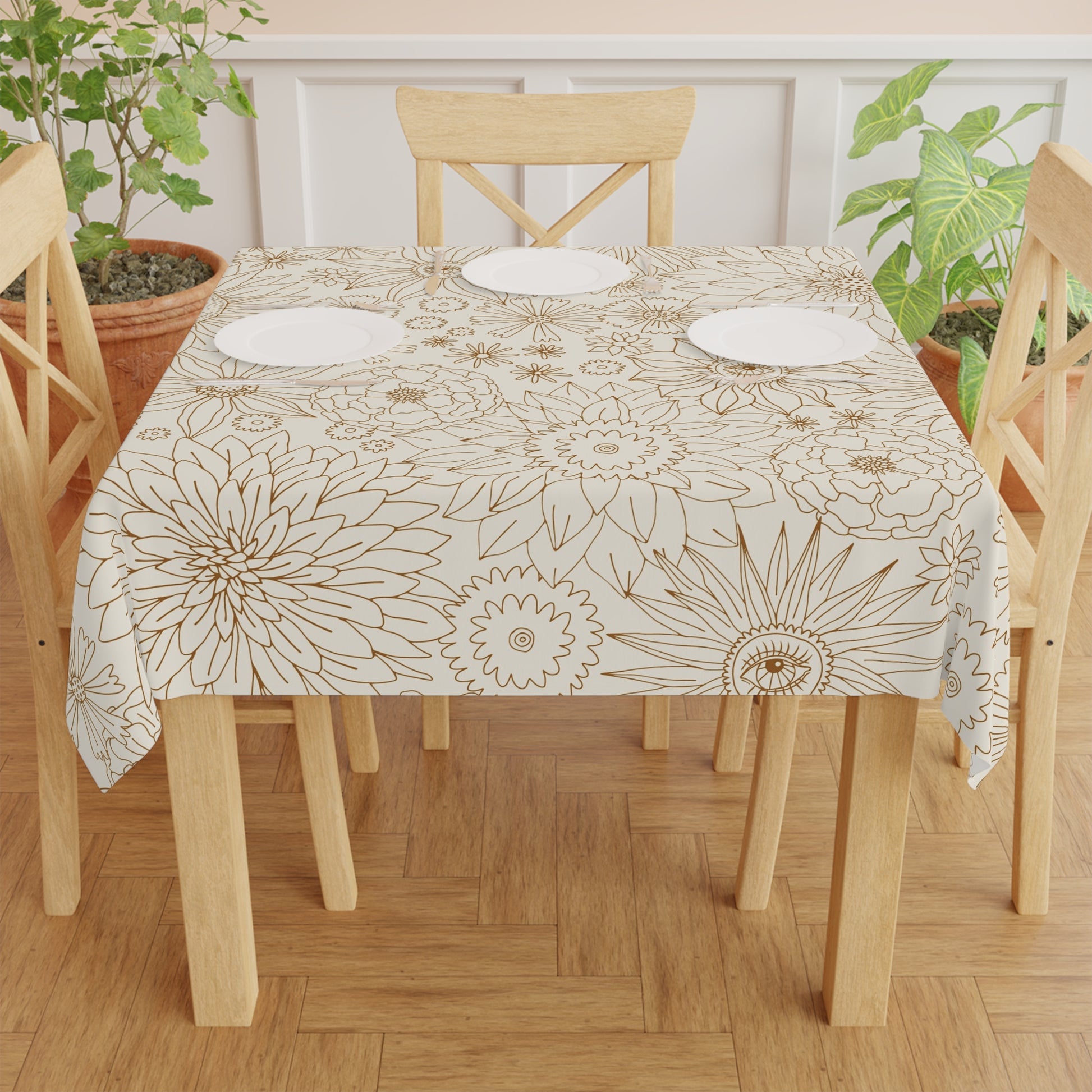 Dining table with floral patterned tablecloth and wooden chairs on a wooden floor.