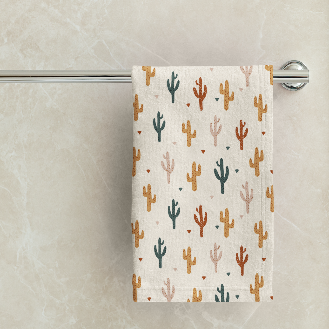 Towel with cactus pattern hanging on a rack against a marble wall.