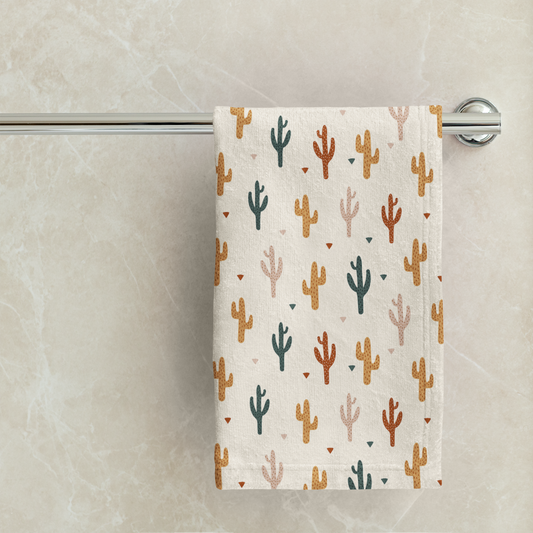 Towel with cactus pattern hanging on a rack against a marble wall.