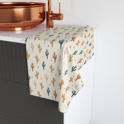 Cactus patterned towel hanging on a towel rack with a copper faucet in the background.