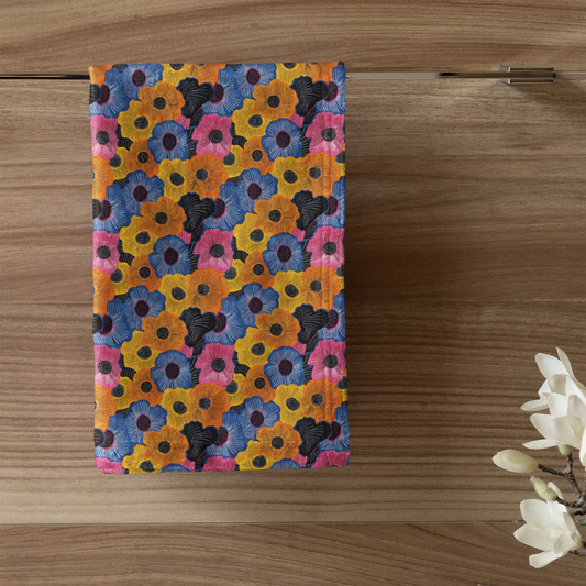 Colorful floral patterned towel hanging on a wooden door with a candle and plant in the foreground.