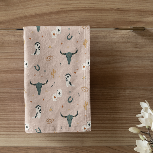 Towel with bull head pattern hanging on a wooden wall above a toilet with a candle and plant.