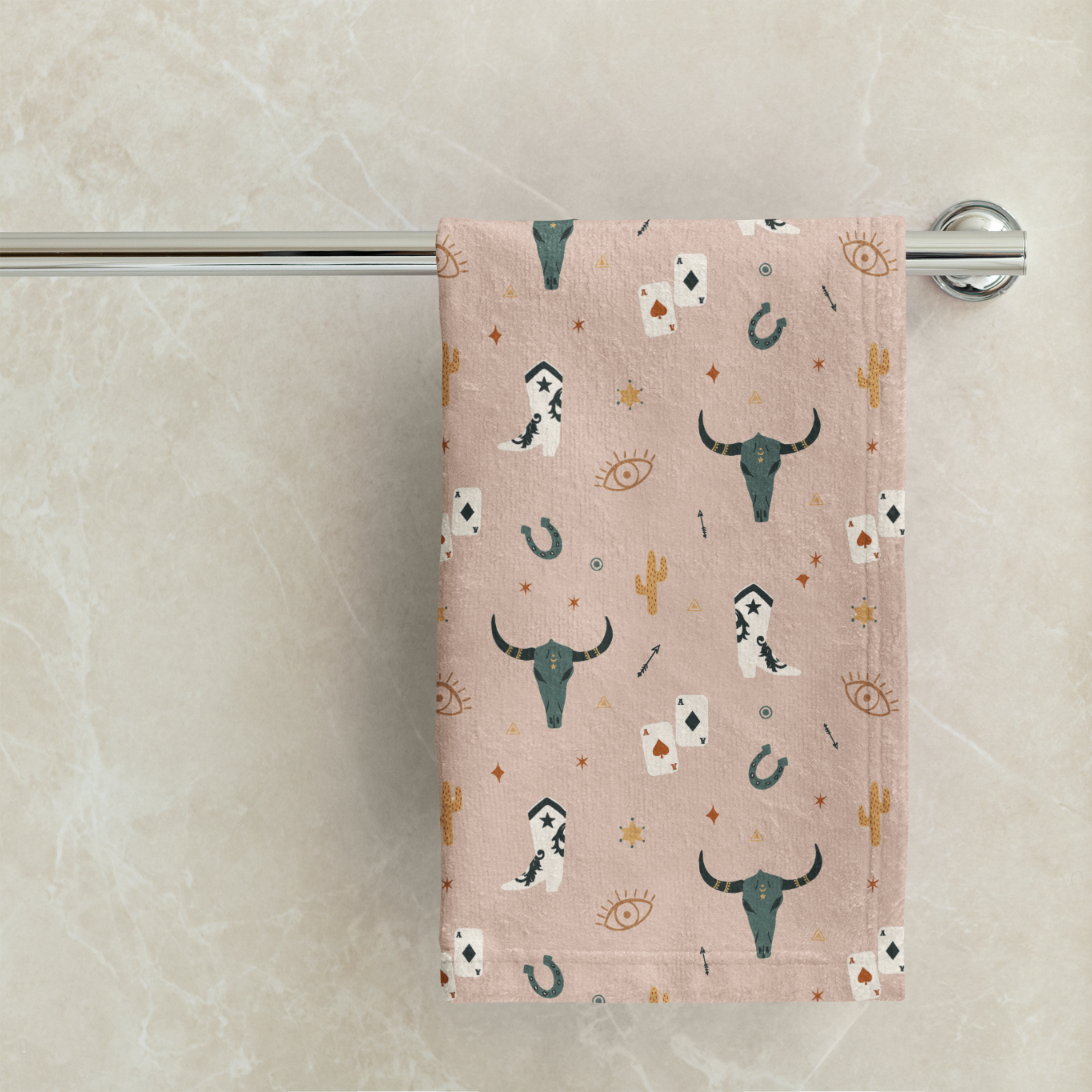 Towel with longhorn cow pattern hanging on a towel rack against a marble wall.