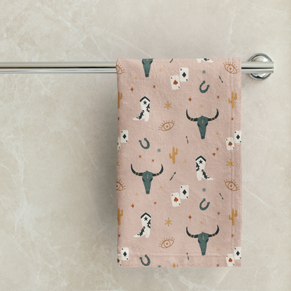 Towel with longhorn cow pattern hanging on a towel rack against a marble wall.
