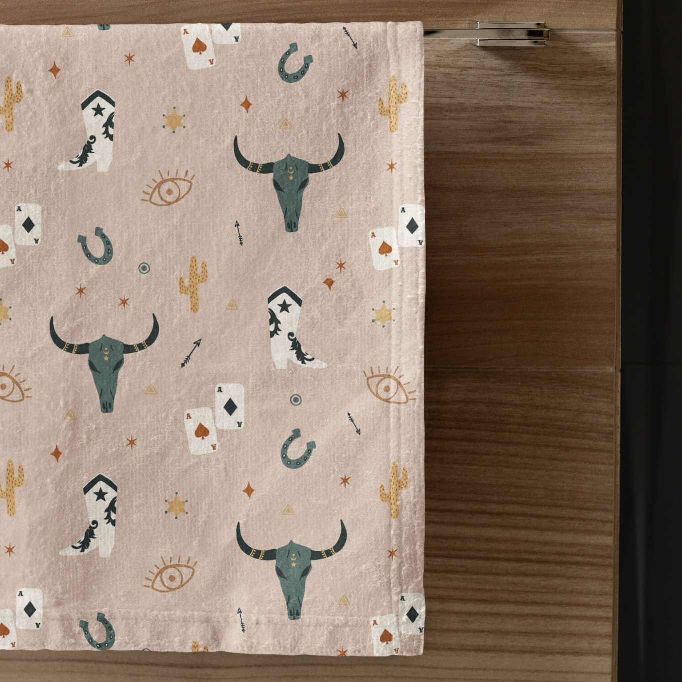 Decorative towel with bull head and cactus pattern on a wooden surface