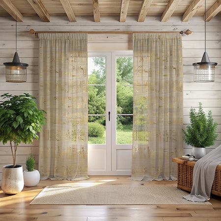 A pair of off-white Egyptian hieroglyphics curtains with gold patterns, hanging in a room with a window, a potted plant, and a chair.