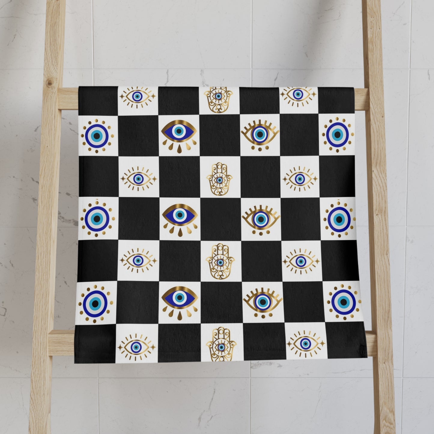 Black and white checkered towel with eye and hand designs on a wooden ladder against a white wall.