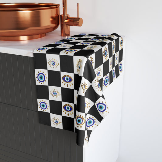 Checkered hand towel with eye pattern on a kitchen counter with copper fixtures.